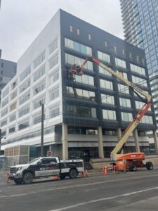 125ft Articulating Boom Lift performing exterior building maintenance on a modern commercial property in an urban environment.