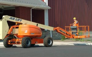 60ft Articulating Boom Lift operated by a worker performing high-reach inspection and maintenance tasks beside an industrial building.