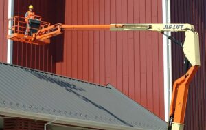 60ft Articulating Boom Lift providing elevated access for exterior building maintenance and siding work on a commercial facility.