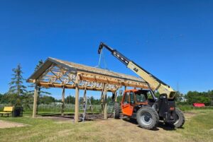 Telehandler lifting roof trusses during construction to improve jobsite efficiency and streamline material handling.