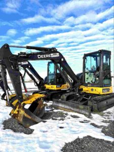Two 5-tonne mini excavators on a job site, illustrating small excavator rental costs and equipment options for construction projects.