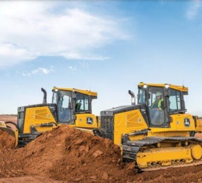 Multiple tracked dozers pushing and grading soil across an active construction site during earthmoving operations.