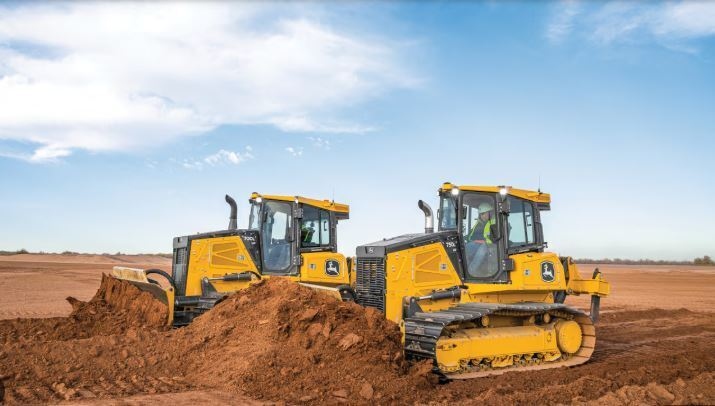 Multiple tracked dozers pushing and grading soil across an active construction site during earthmoving operations.