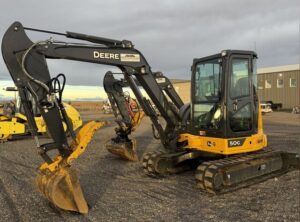Mid-size excavator with digging bucket at an equipment yard.