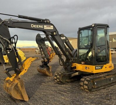 Mid-size excavator with digging bucket at an equipment yard.